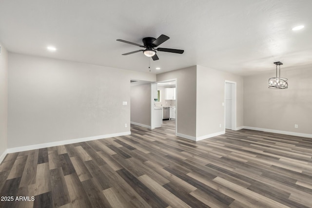 unfurnished living room with recessed lighting, baseboards, dark wood-style floors, and ceiling fan with notable chandelier