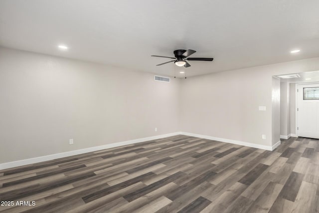 spare room with ceiling fan, visible vents, baseboards, and dark wood-style floors