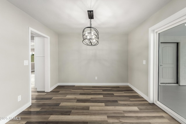 unfurnished dining area with baseboards, a notable chandelier, and dark wood-style floors