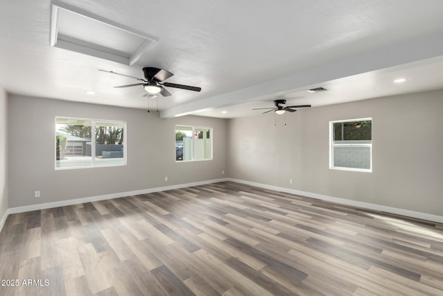 empty room with ceiling fan, visible vents, baseboards, and wood finished floors