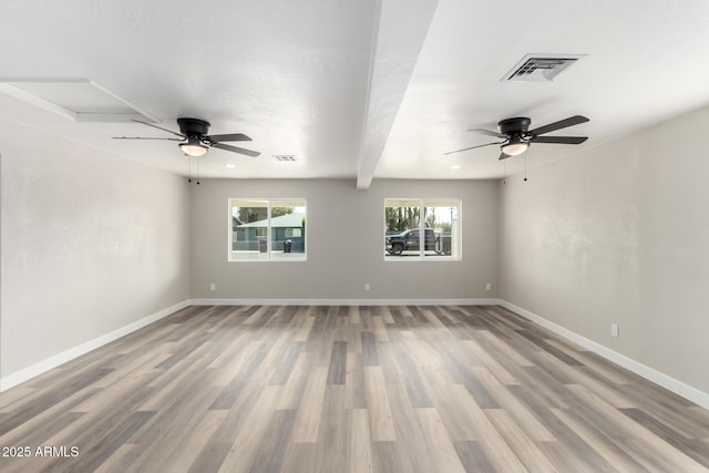 empty room featuring visible vents, a ceiling fan, and wood finished floors