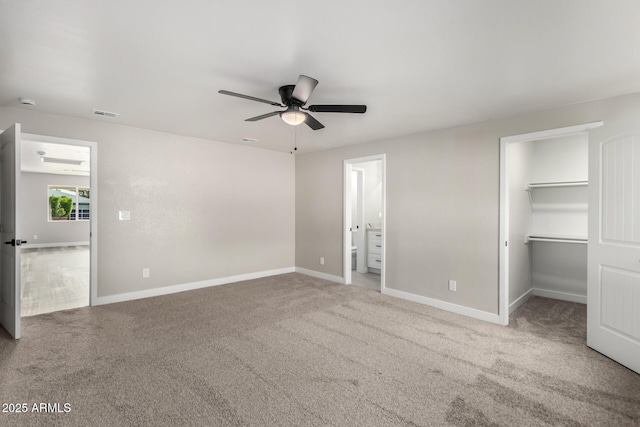 unfurnished bedroom featuring a walk in closet, carpet flooring, visible vents, and baseboards