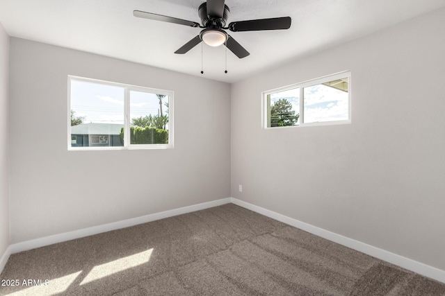 carpeted empty room with a ceiling fan, baseboards, and a wealth of natural light