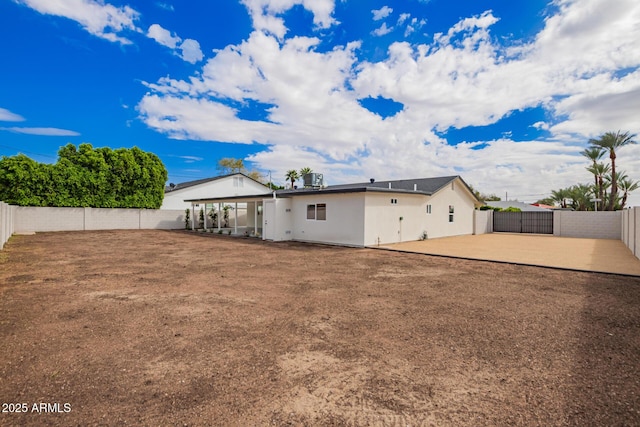 rear view of house featuring a fenced backyard, stucco siding, a patio, and a gate