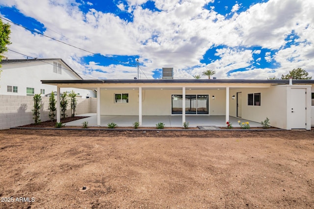 rear view of property featuring a patio, fence, and stucco siding