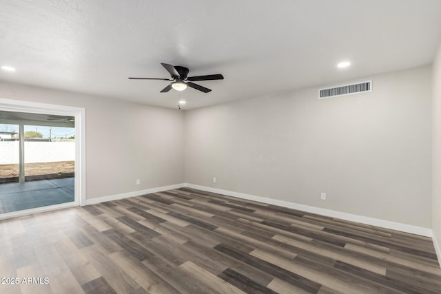 empty room with visible vents, a ceiling fan, baseboards, and dark wood-style flooring