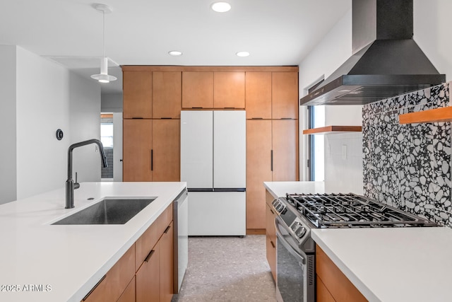 kitchen with pendant lighting, stainless steel appliances, wall chimney range hood, tasteful backsplash, and sink