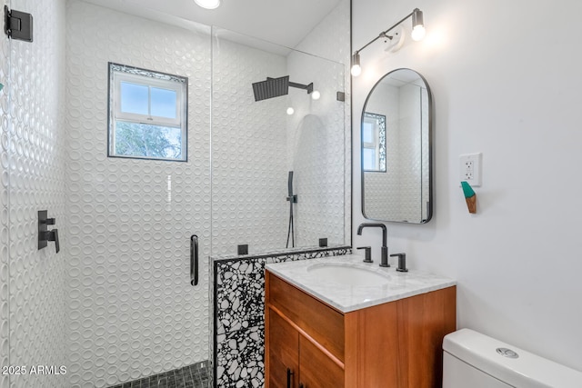 bathroom with toilet, vanity, and a shower with shower door