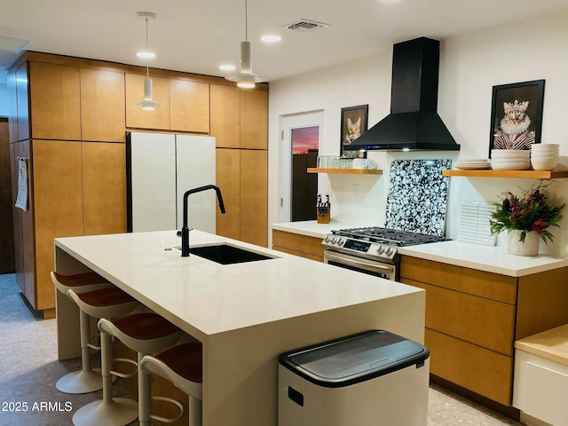 kitchen with sink, white refrigerator, stainless steel gas range, backsplash, and exhaust hood