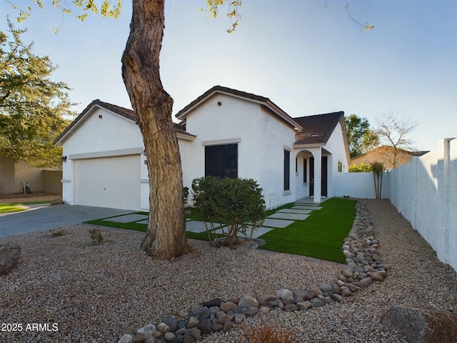 view of front facade featuring a garage, fence, concrete driveway, and stucco siding