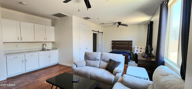1005 W Lincoln Ave, Coolidge, AZ 85128 - living area with ceiling fan, a barn door, dark wood-style flooring, and baseboards