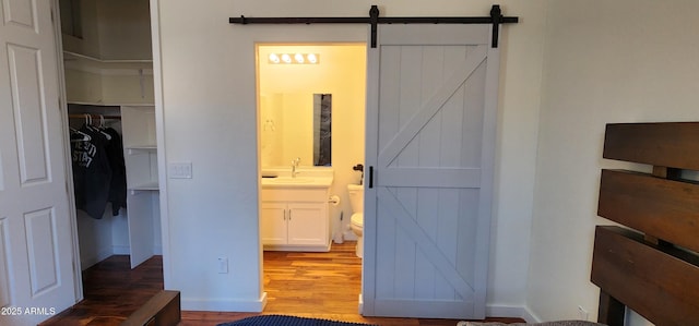 1005 W Lincoln Ave, Coolidge, AZ 85128 - unfurnished bedroom with a barn door, a walk in closet, wood finished floors, a closet, and ensuite bathroom