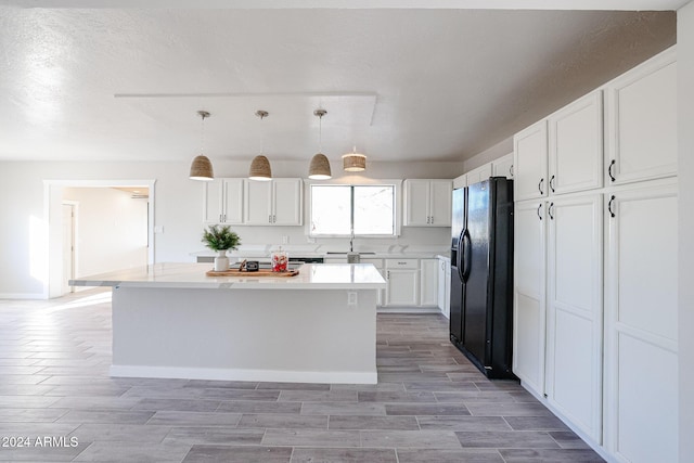 kitchen with pendant lighting, black fridge with ice dispenser, a kitchen island, and white cabinets