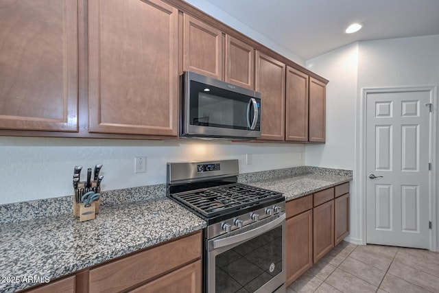 kitchen featuring appliances with stainless steel finishes, dark stone countertops, and light tile patterned floors