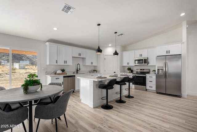 kitchen featuring a breakfast bar area, light countertops, visible vents, appliances with stainless steel finishes, and a sink