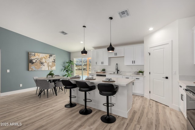 kitchen featuring visible vents, white cabinets, and a sink