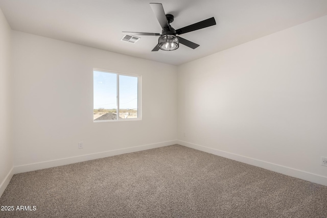 carpeted spare room with baseboards, visible vents, and a ceiling fan