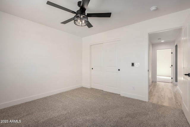 unfurnished bedroom with a ceiling fan, baseboards, a closet, and light colored carpet