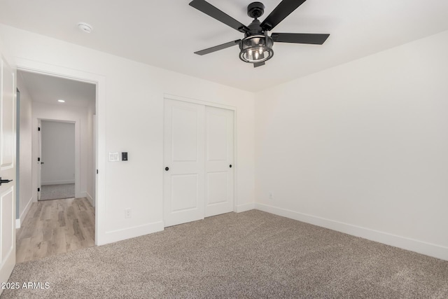 unfurnished bedroom featuring a ceiling fan, baseboards, a closet, and light colored carpet