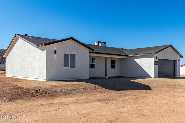 view of front facade with a garage, roof with shingles, and stucco siding