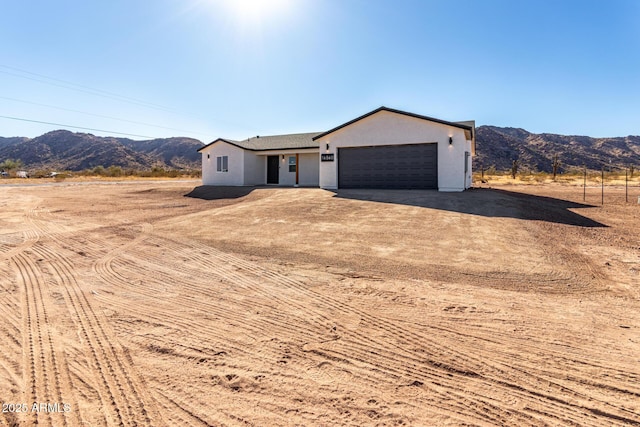 view of front of house with driveway, an attached garage, a mountain view, and stucco siding