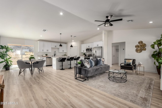 living room with vaulted ceiling, ceiling fan, light wood-type flooring, and visible vents