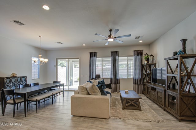 living room with ceiling fan with notable chandelier