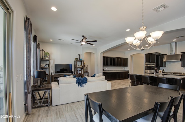 dining room with plenty of natural light, sink, ceiling fan with notable chandelier, and light hardwood / wood-style flooring