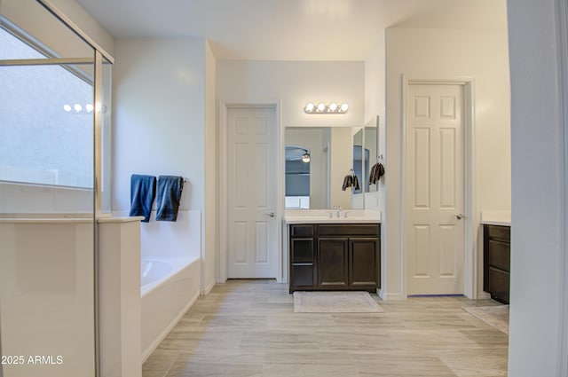 bathroom with a washtub and vanity