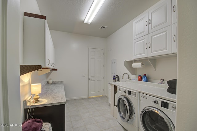 laundry area with washer and clothes dryer, a textured ceiling, and cabinets