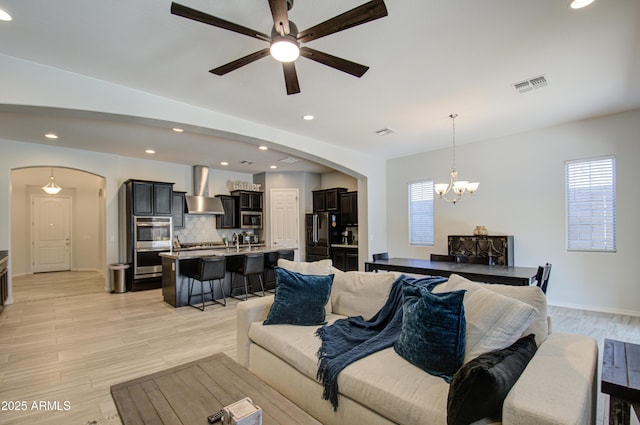 living room with ceiling fan with notable chandelier and light hardwood / wood-style floors