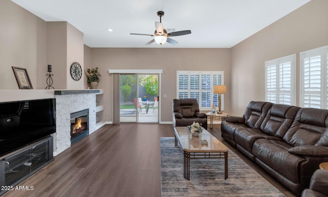 living room featuring dark hardwood / wood-style flooring, ceiling fan, and a fireplace