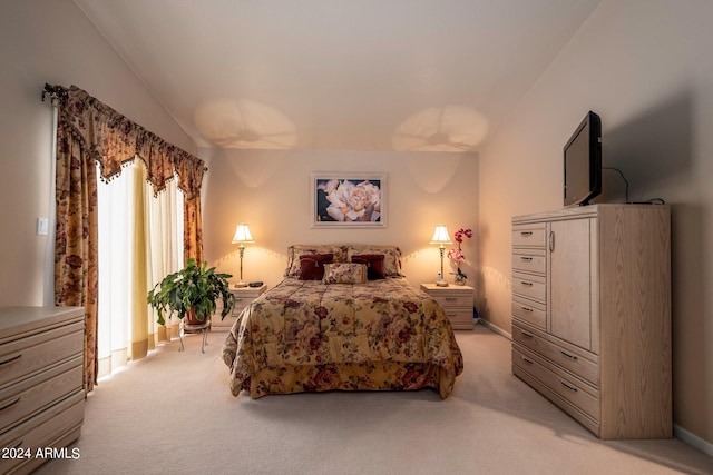 bedroom with light colored carpet and lofted ceiling