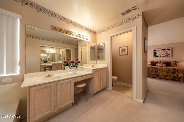 bathroom featuring toilet and double vanity