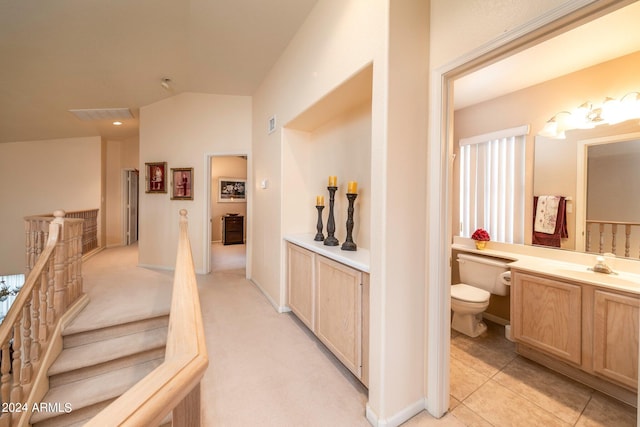 corridor with lofted ceiling, light tile floors, and sink