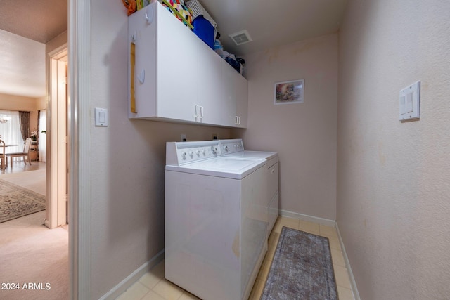 clothes washing area featuring cabinets, light carpet, and separate washer and dryer