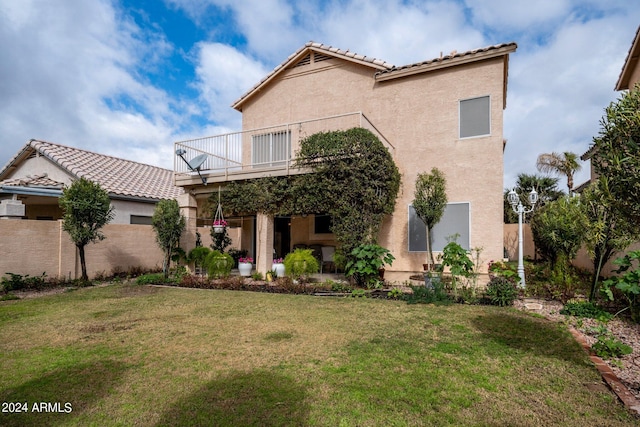 rear view of property with a yard and a balcony