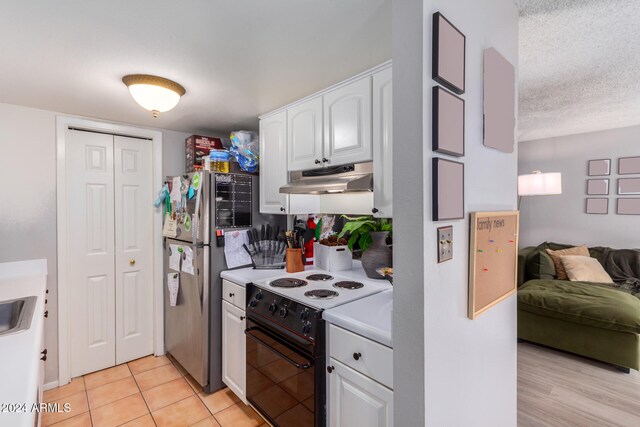 kitchen with light tile patterned flooring, stainless steel refrigerator, a textured ceiling, white cabinets, and white electric range