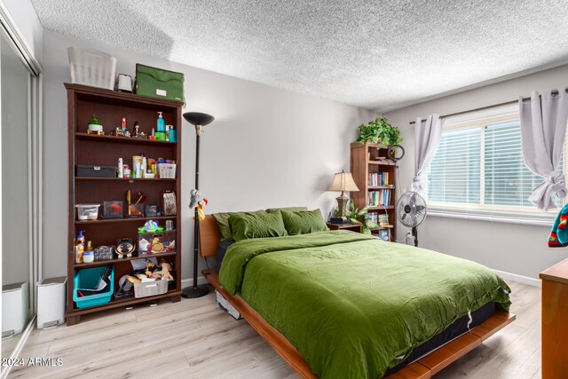 bedroom featuring a textured ceiling, a closet, and light hardwood / wood-style flooring