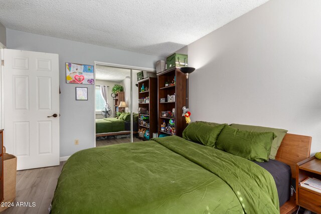 bedroom with wood-type flooring, a textured ceiling, and a closet