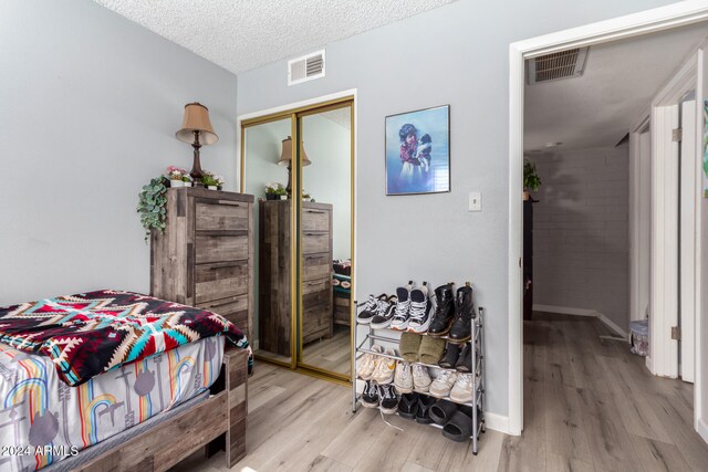 bedroom featuring light hardwood / wood-style floors, a textured ceiling, and a closet