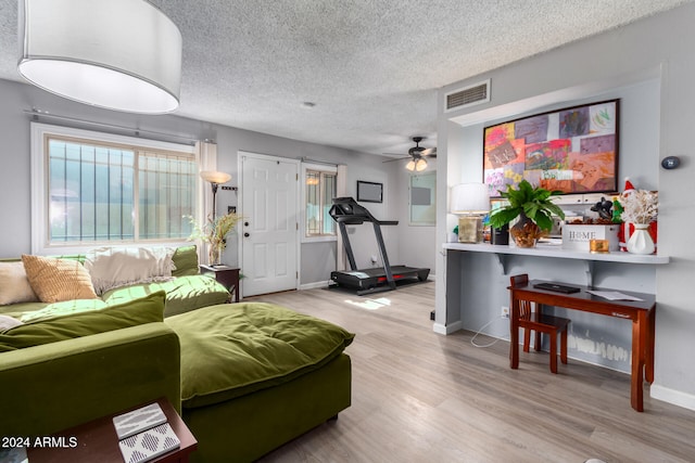 living room featuring a textured ceiling, light hardwood / wood-style floors, and ceiling fan