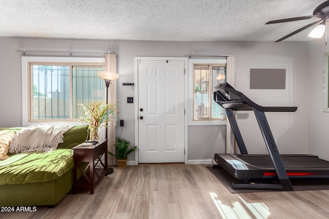 exercise area featuring light hardwood / wood-style floors, ceiling fan, and a textured ceiling