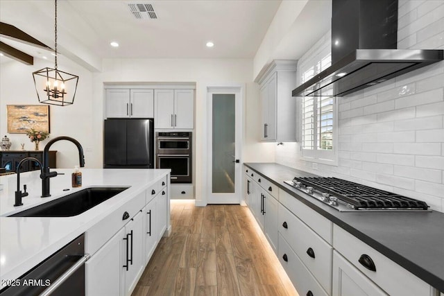 17146 W Mountainair St, Surprise, AZ 85388 - kitchen featuring wall chimney range hood, stainless steel appliances, a sink, wood finished floors, and decorative backsplash