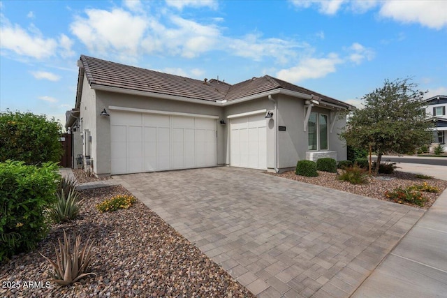 17146 W Mountainair St, Surprise, AZ 85388 - view of property exterior featuring an attached garage, a tile roof, decorative driveway, and stucco siding