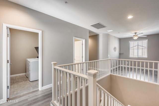 hall with light wood-type flooring and separate washer and dryer