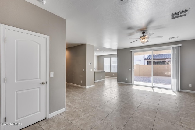 spare room with ceiling fan, light tile patterned floors, and a textured ceiling