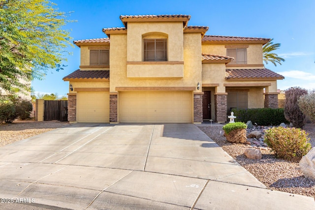 mediterranean / spanish home with an attached garage, fence, concrete driveway, and stucco siding