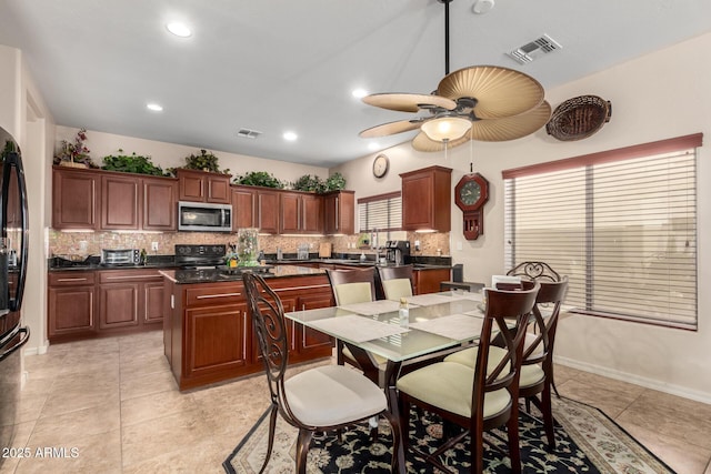 kitchen featuring electric range, visible vents, dark countertops, a kitchen island, and stainless steel microwave