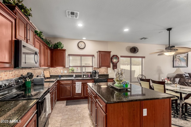 kitchen featuring a sink, a kitchen island, visible vents, black electric range, and stainless steel microwave